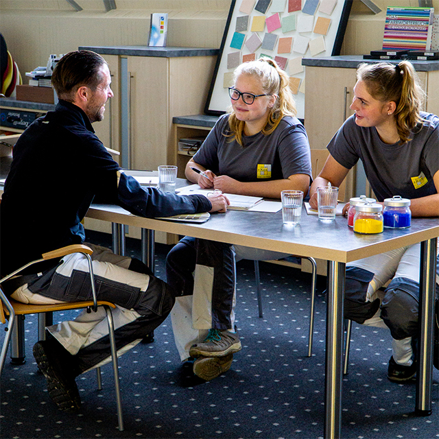 Niklas Scholler mit Auszubildenden an einem Tisch